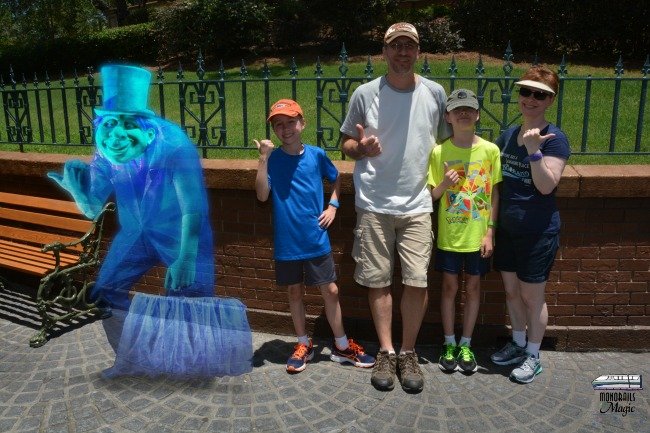 Reasons to use Disney's PhotoPass service. Family with magic shot outside of Haunted Mansion at Magic Kingdom.